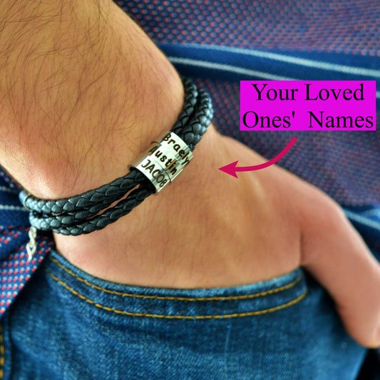 A close-up of a person's wrist wearing a dark braided leather bracelet with a silver engraved nameplate that reads 'for your loving Jack'. A pink text bubble says 'Your Loved Ones' Names' with an arrow pointing to the bracelet.