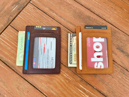 Two slim leather card wallets displayed side-by-side on a wooden surface. The left wallet is dark brown and holds credit cards and cash.
