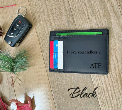 A black leather card holder wallet with custom engraving reading 'I love you endlessly.