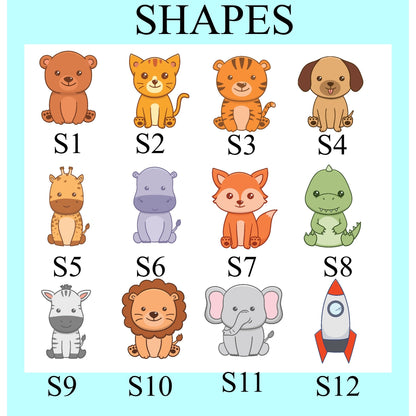 A labeled educational chart titled "SHAPES" showing twelve cartoon animal and object shapes arranged in a grid, each with a code such as S1, S2, S3, etc. The chart includes a brown bear, orange cat, tiger, dog, giraffe, hippo, fox, dinosaur, zebra, lion, elephant, rocket, and a green dinosaur-like creature on a white panel with a light blue border.